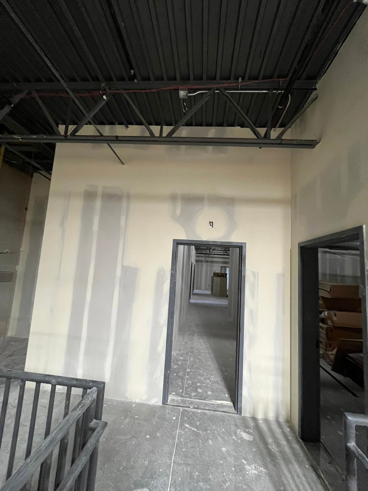 A long hallway with a staircase leading to a doorway in a building under construction.