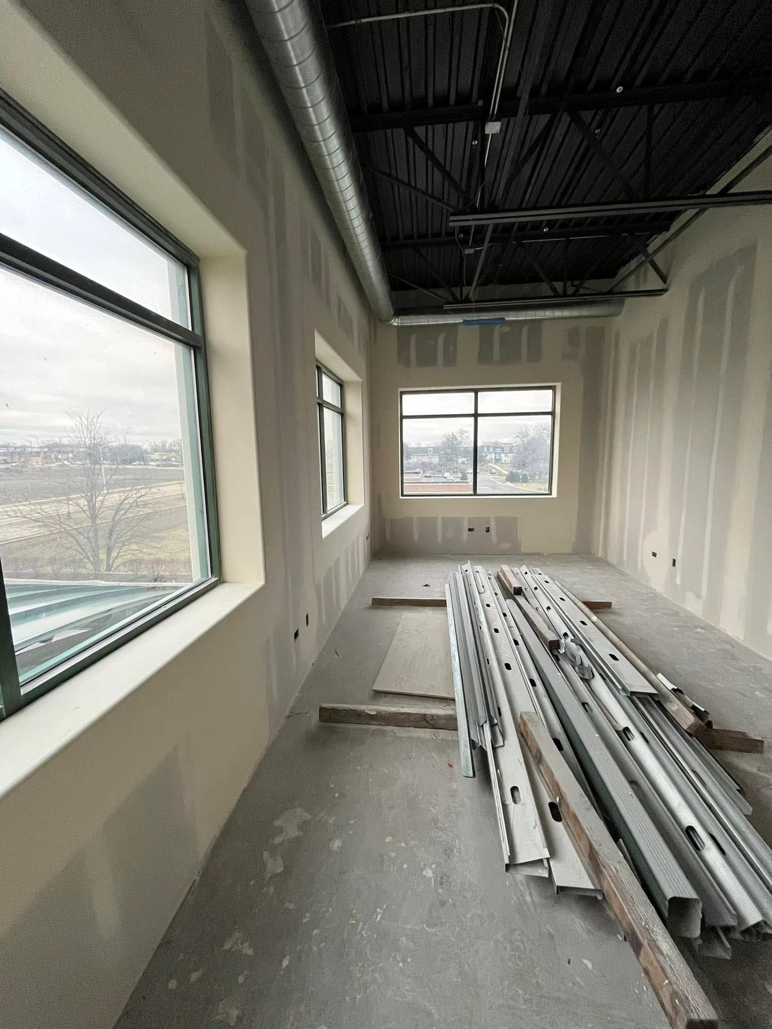A room with a lot of windows and a stack of metal beams on the floor.