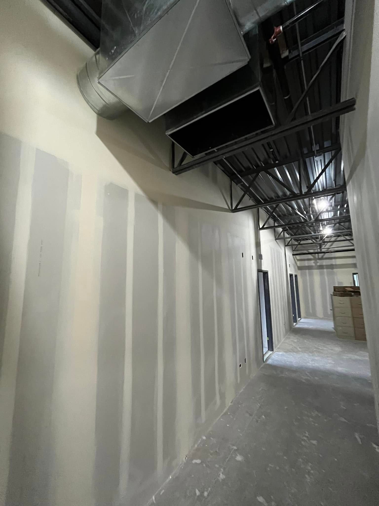 A long hallway with a lot of ducts hanging from the ceiling.