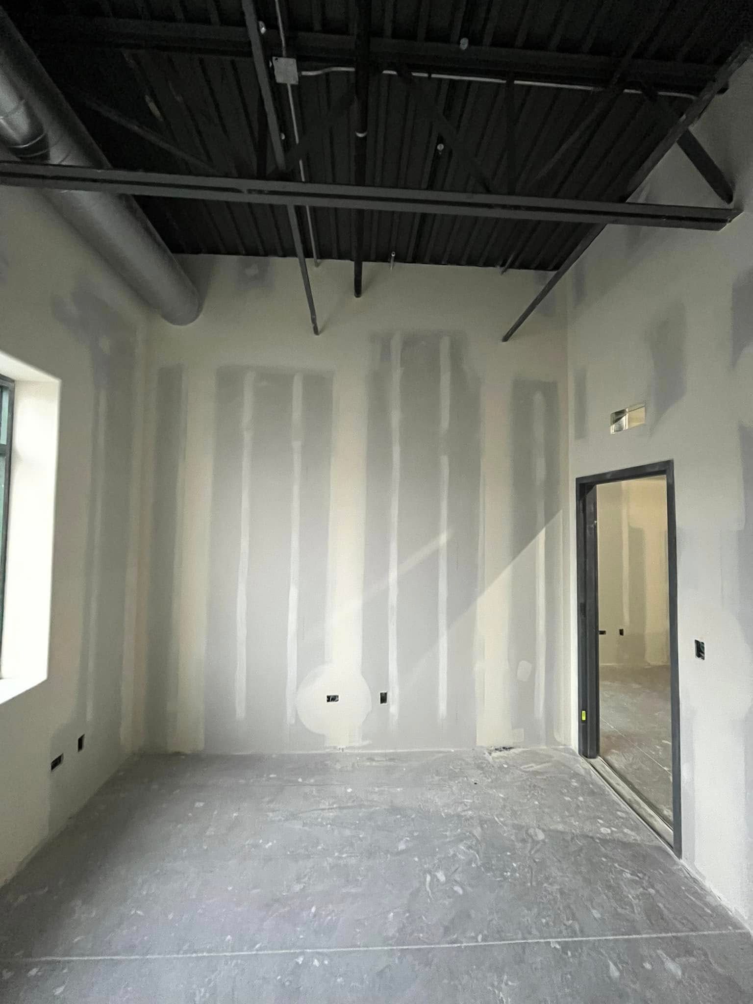 An empty room with drywall on the walls and a door.