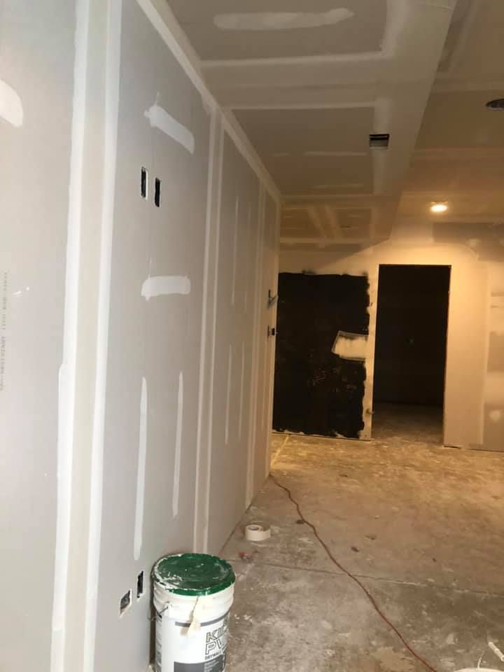 A bucket of paint is sitting on the floor in a room under construction.