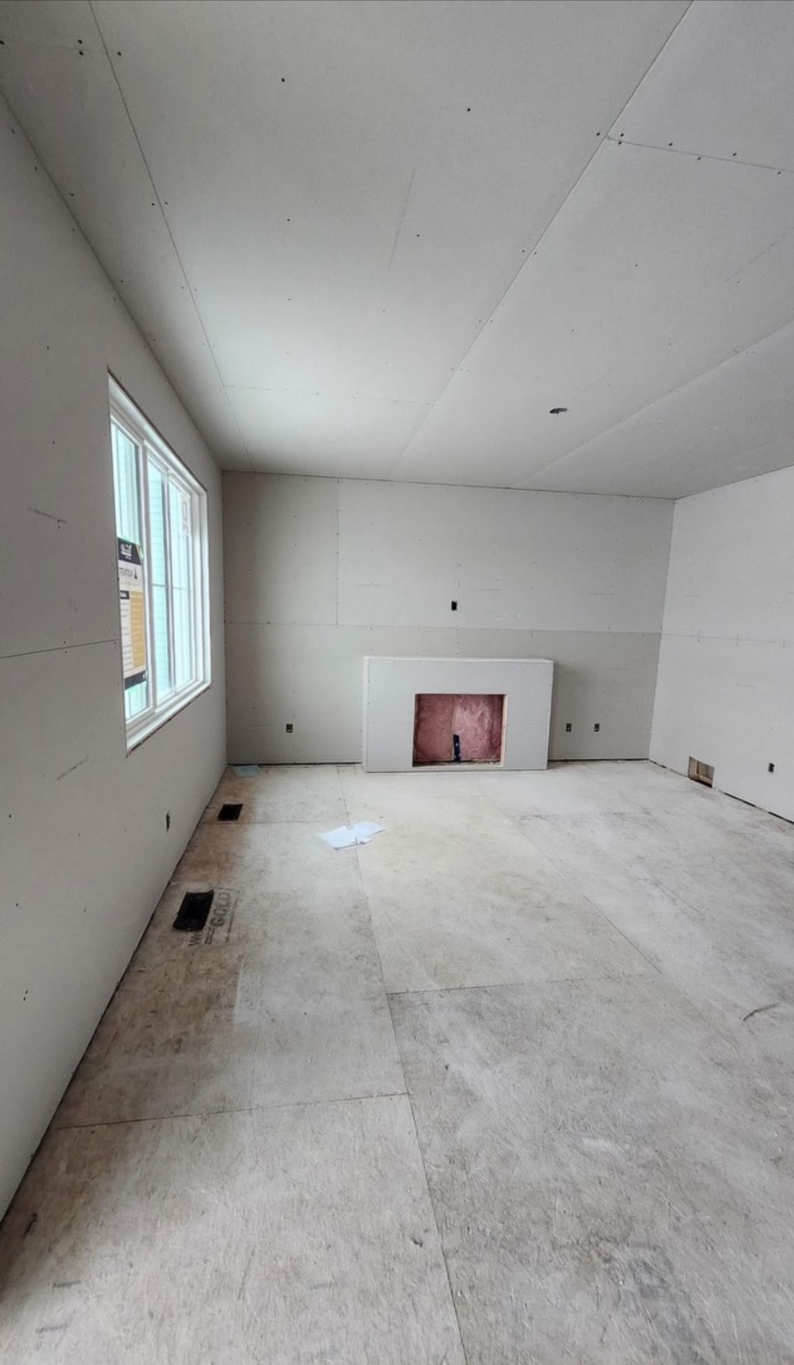 An empty living room with a fireplace and a window.