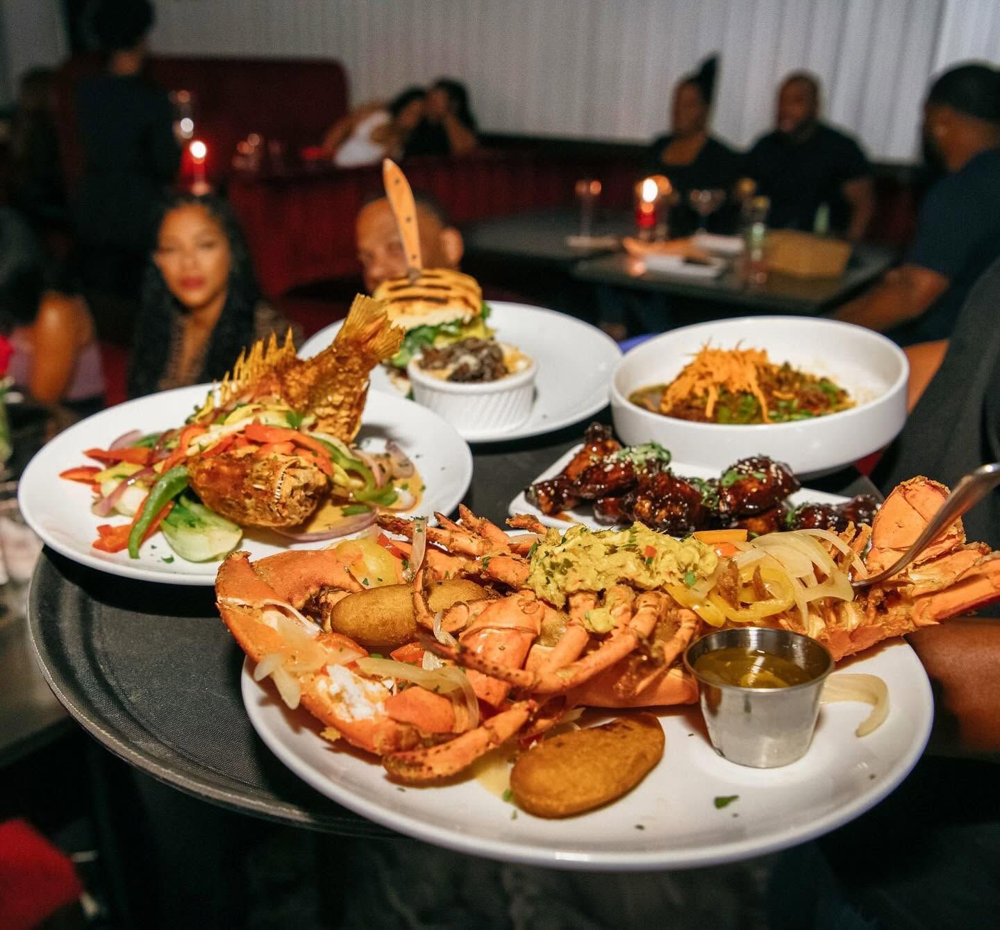 Seafood platter on a restaurant table with crab legs, shrimp, and side dishes; diners blurred in the background