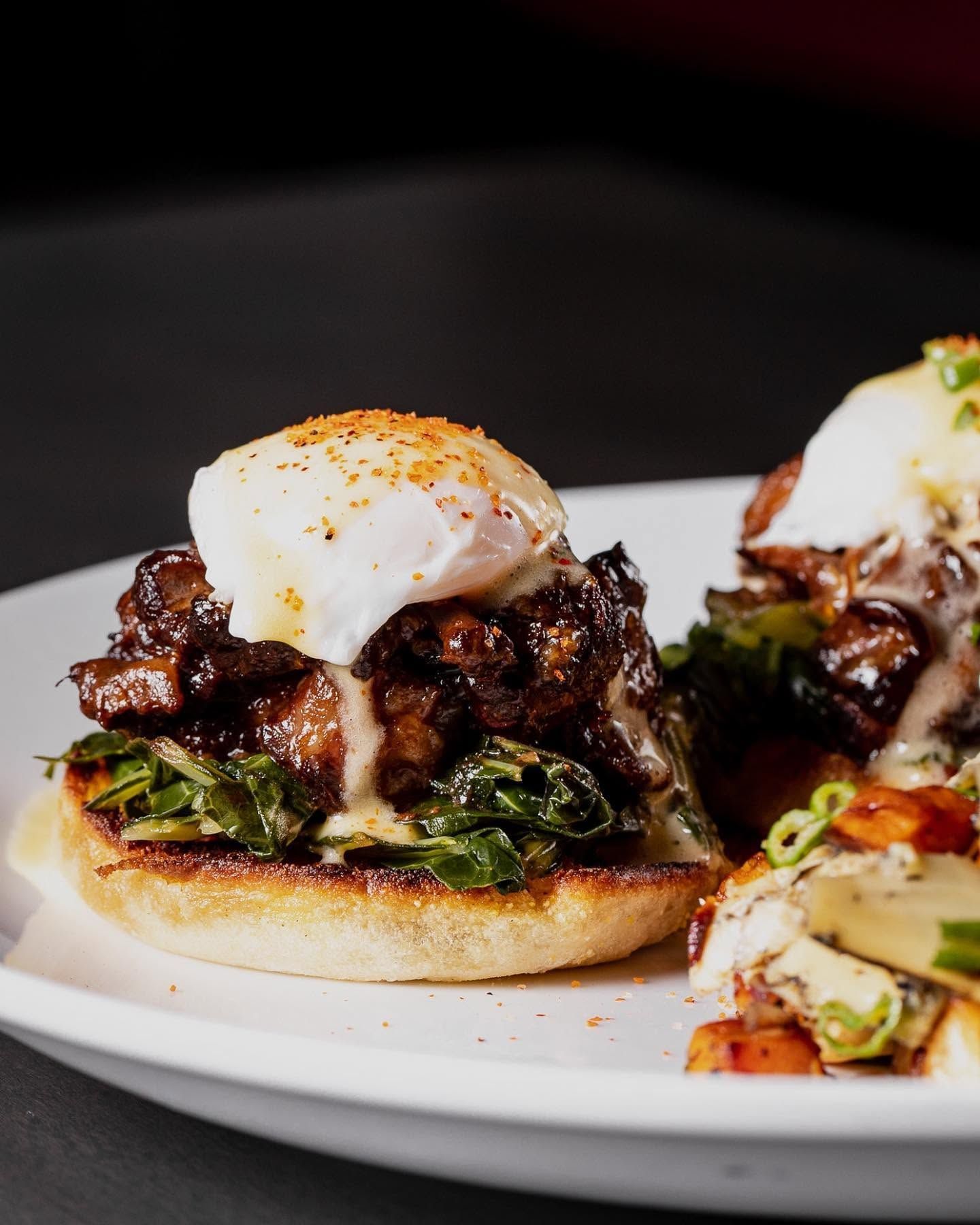Gourmet sliders with poached eggs on a white plate, topped with herbs and sauce