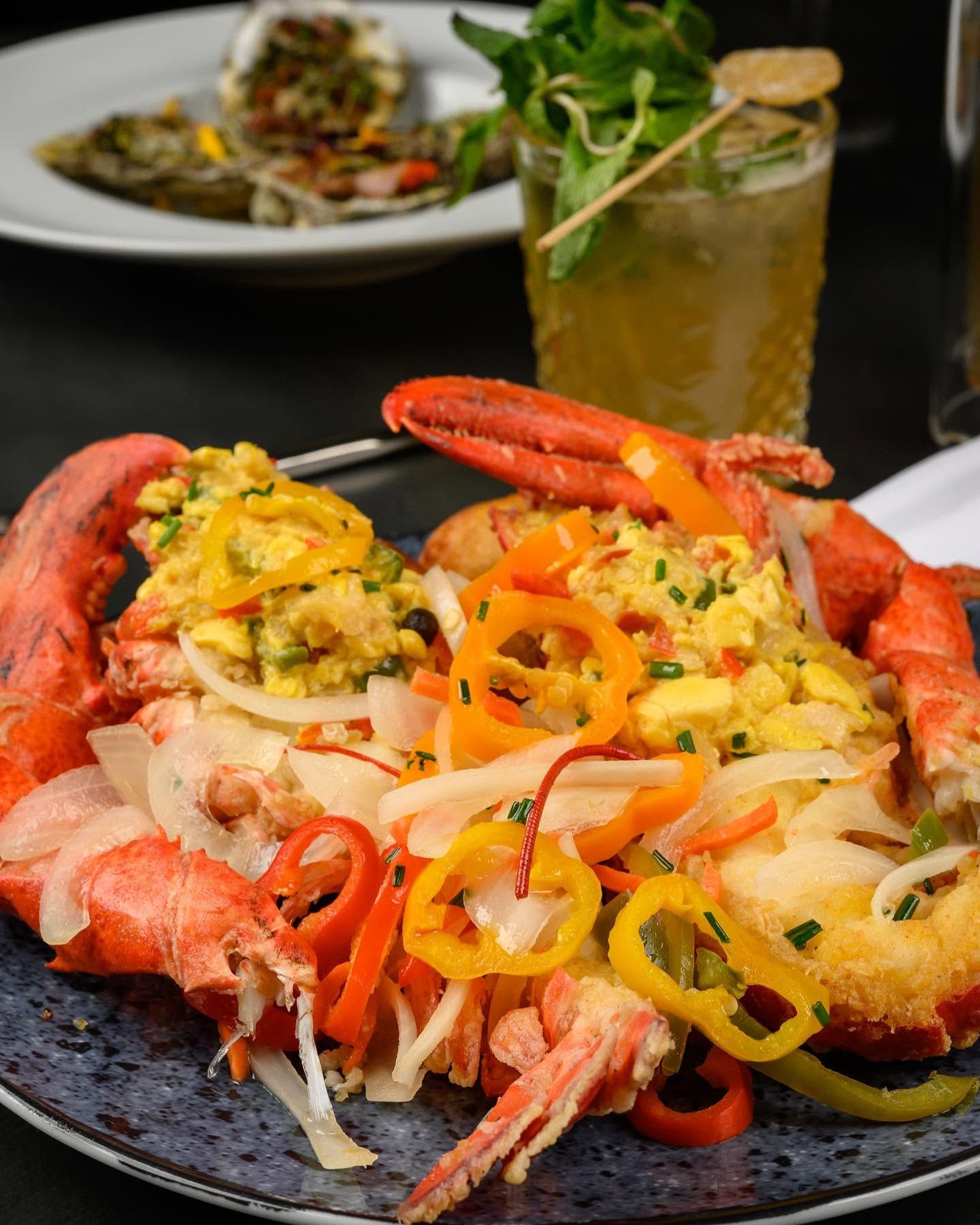 Seafood platter with lobster, crab, and shrimp on toast, topped with colorful peppers and onions