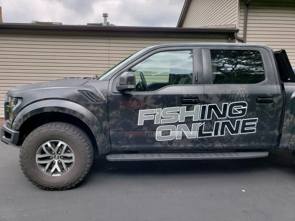 A fishing online truck is parked in front of a house.