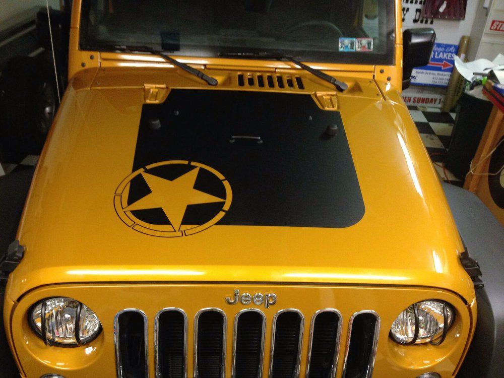 A yellow jeep with a black star on the hood