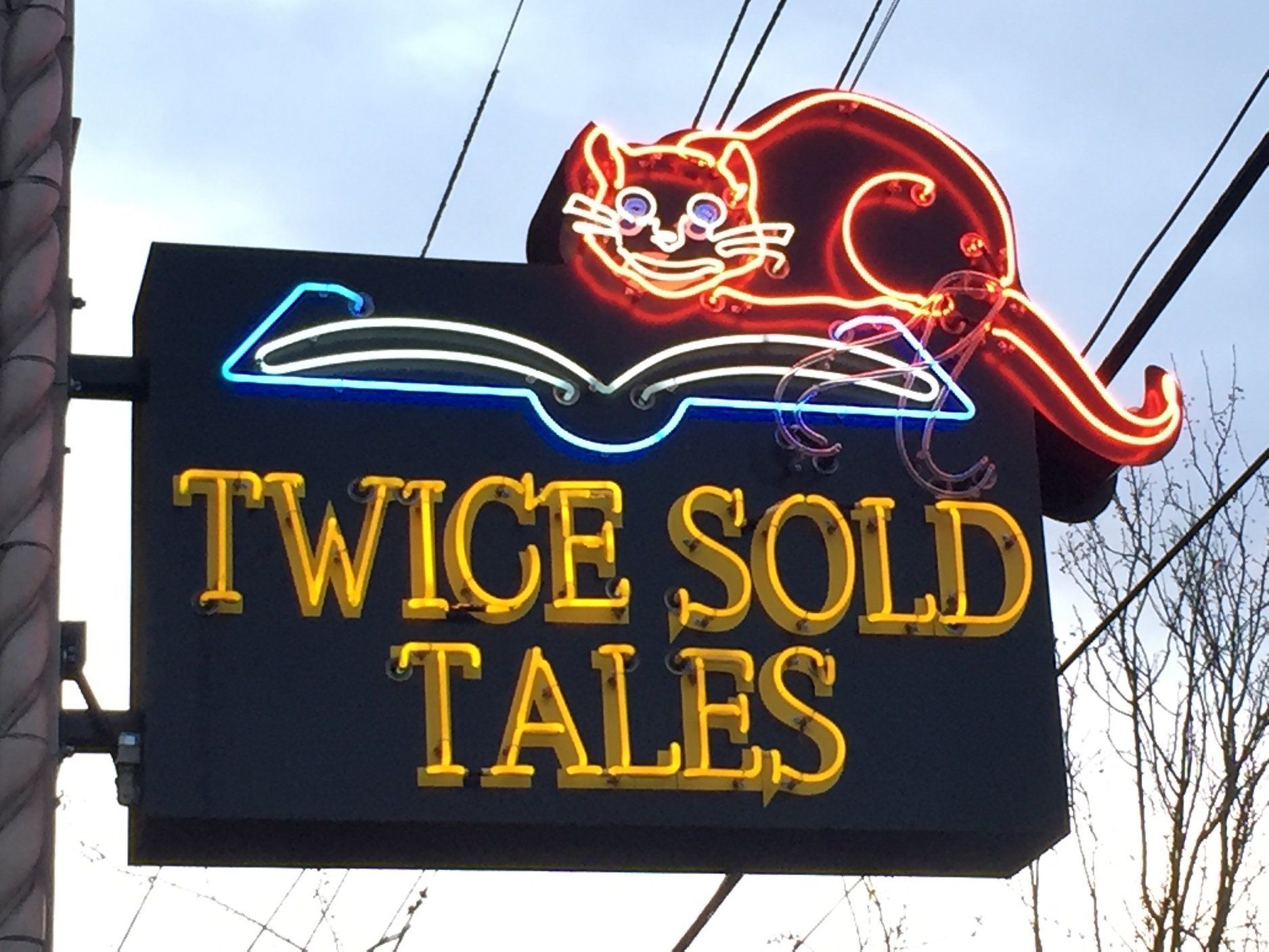 A neon sign for twice sold tales with a cat on a book