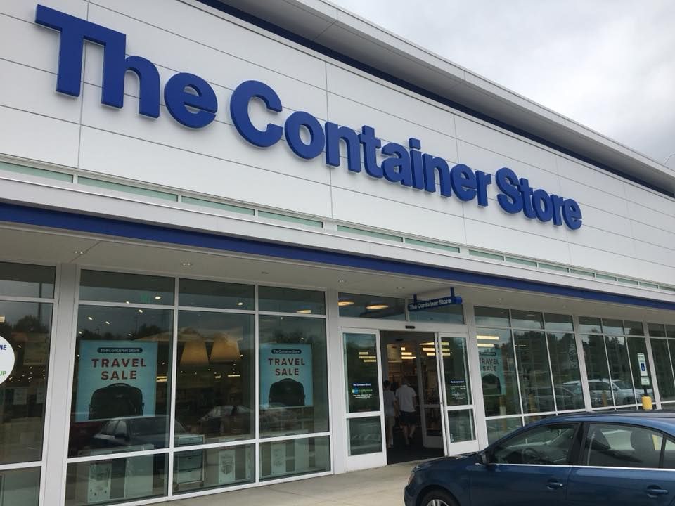 A blue car is parked in front of the container store