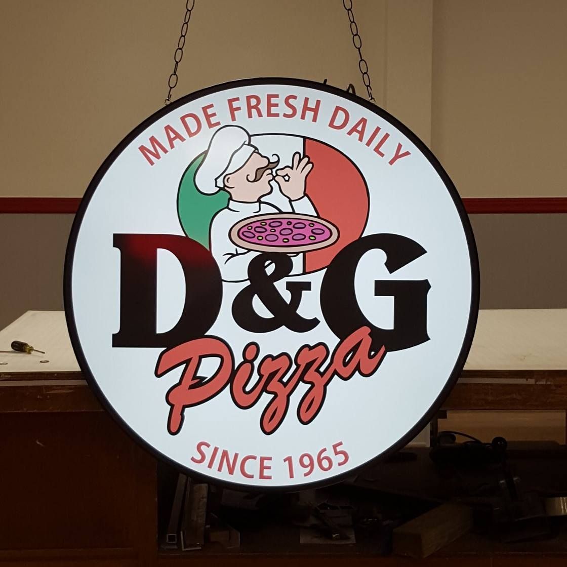 A sign that says d & g pizza made fresh daily