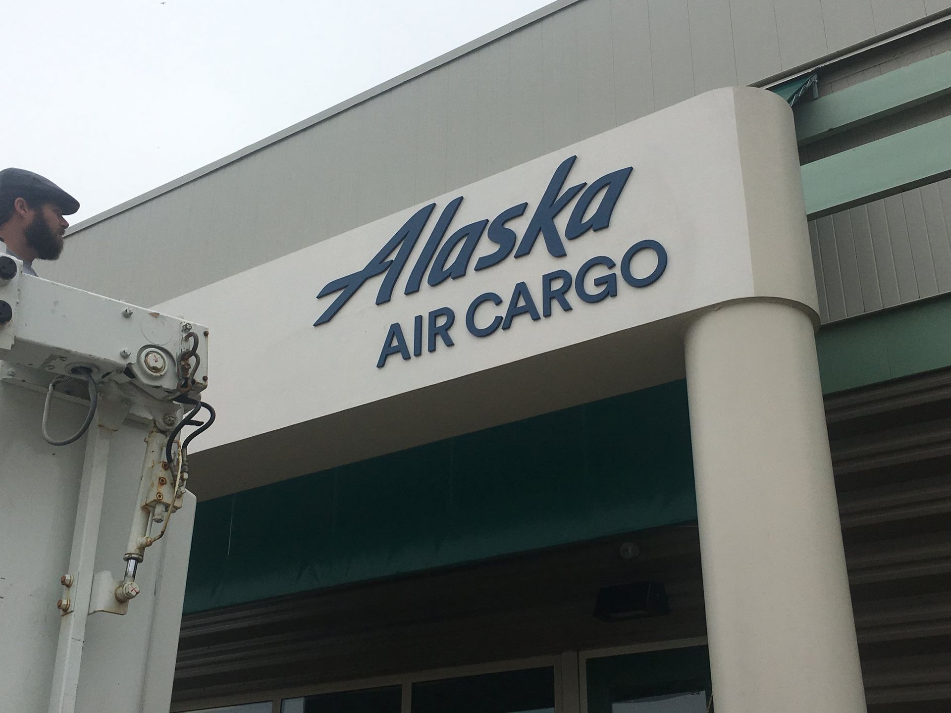 A sign for alaska air cargo hangs from the side of a building