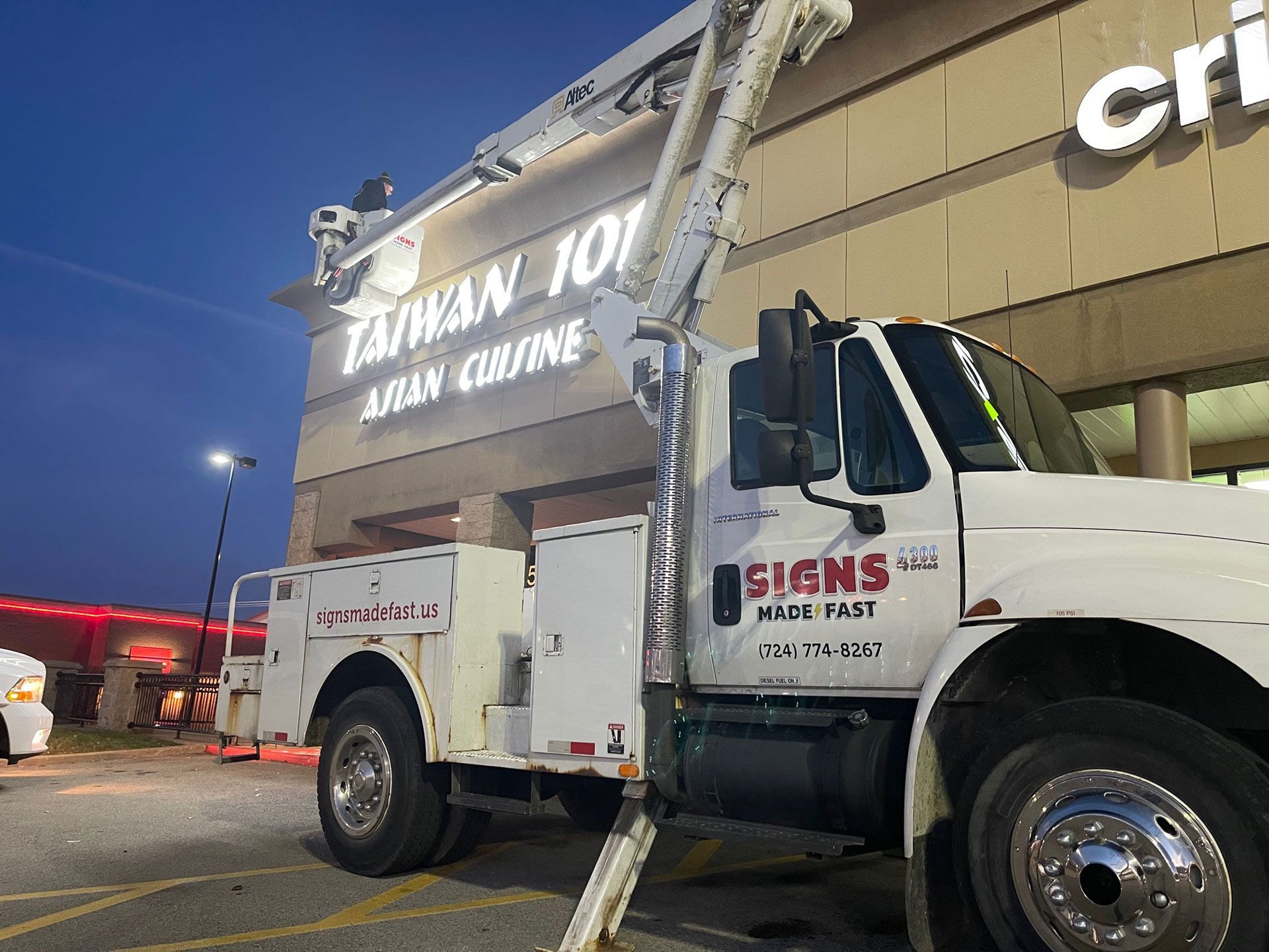 A white signs all truck is parked in front of a building