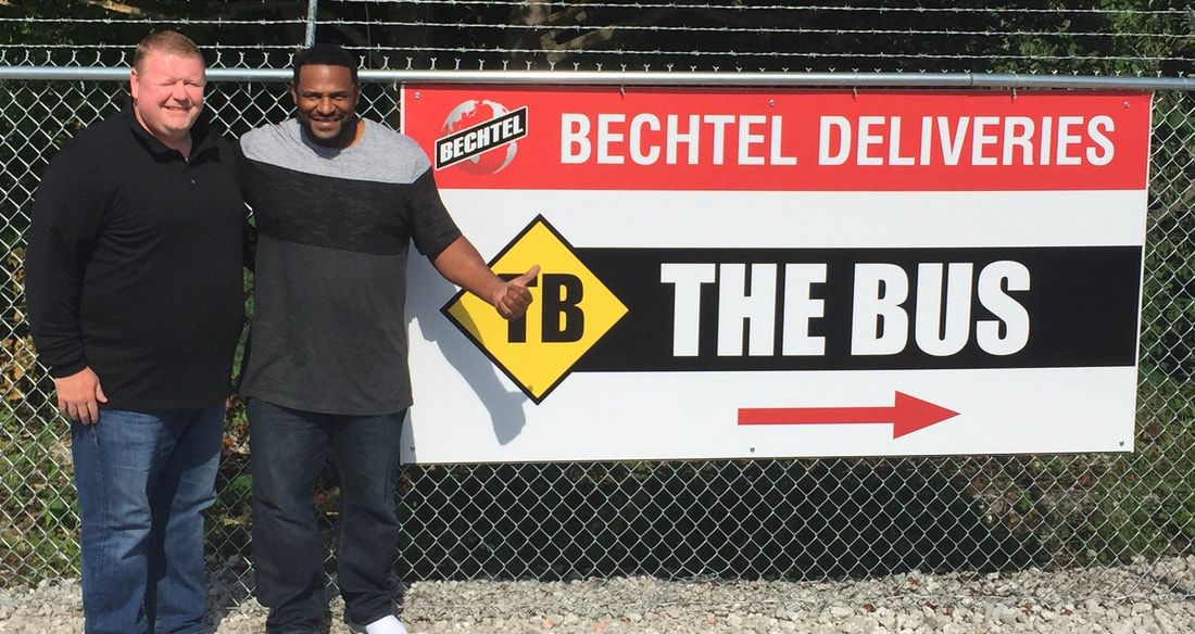 Two men standing in front of a sign