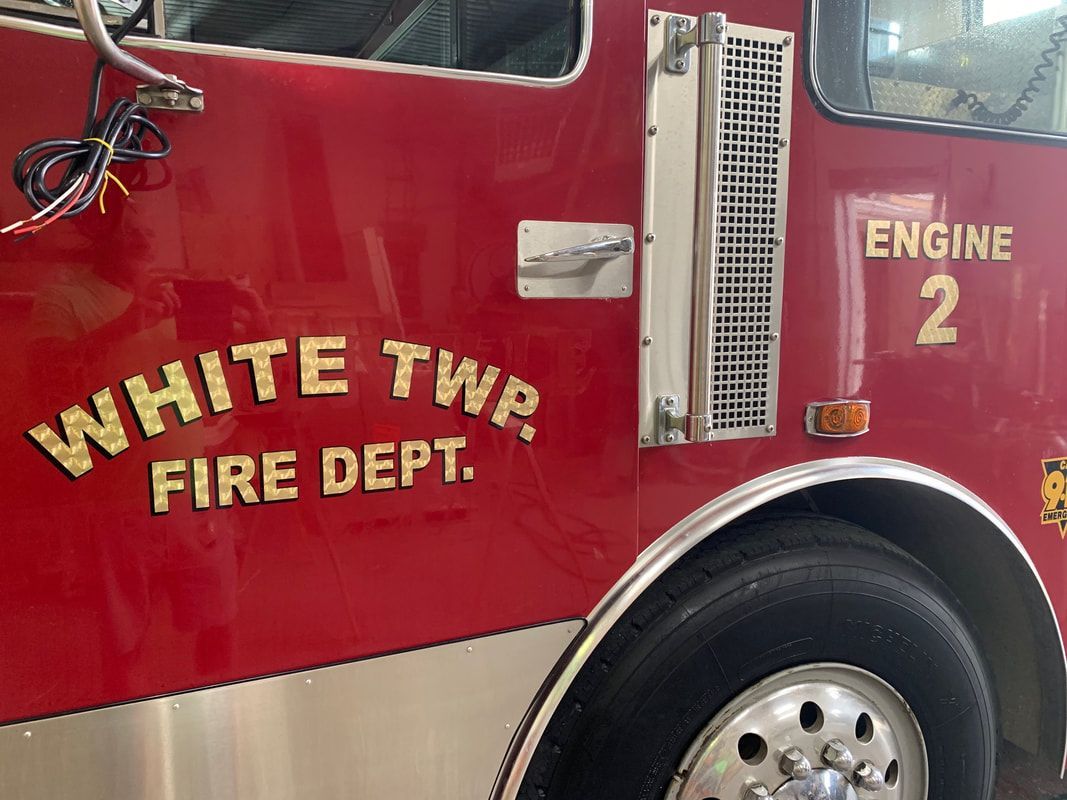A red fire truck from the white twp fire department is parked in a garage.