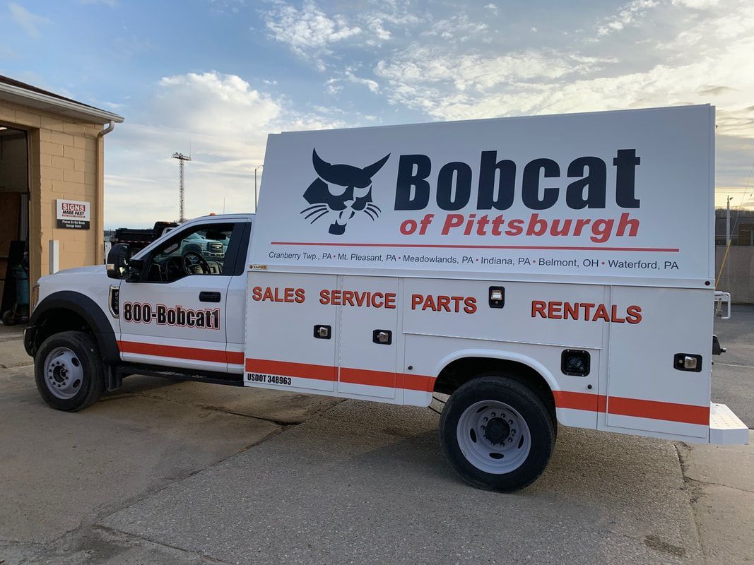 A bobcat truck is parked in front of a building