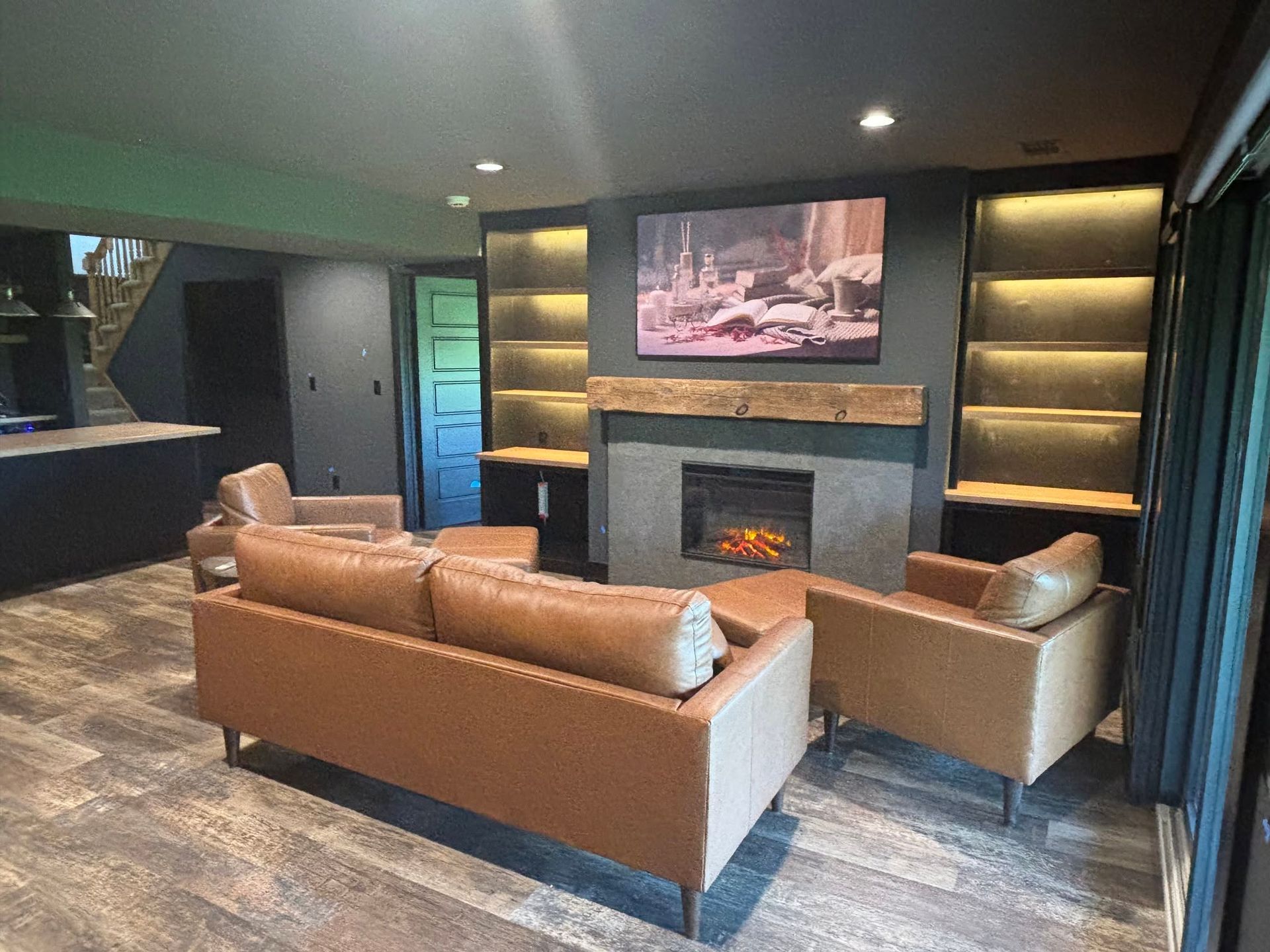 Modern living room with brown sofas, fireplace, wall art, and built-in shelves in a dark interior.