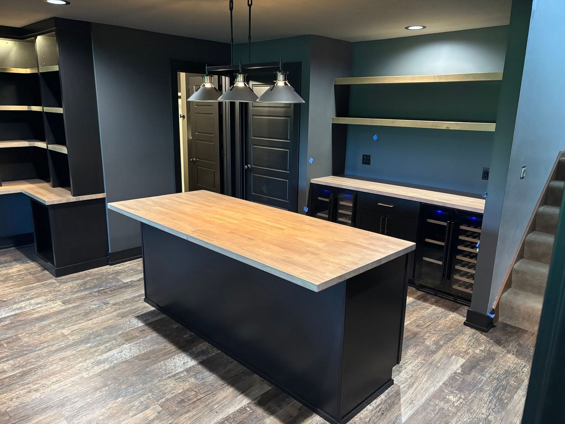 Modern kitchen with large island, dark cabinets, stainless fridge, and blue walls