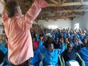 A man leading a lively classroom with enthusiastic children.