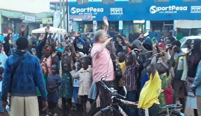A man on a bicycle surrounded by a crowd of people.