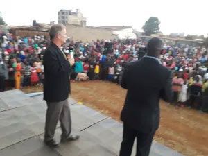 Two men on stage, facing a crowd.