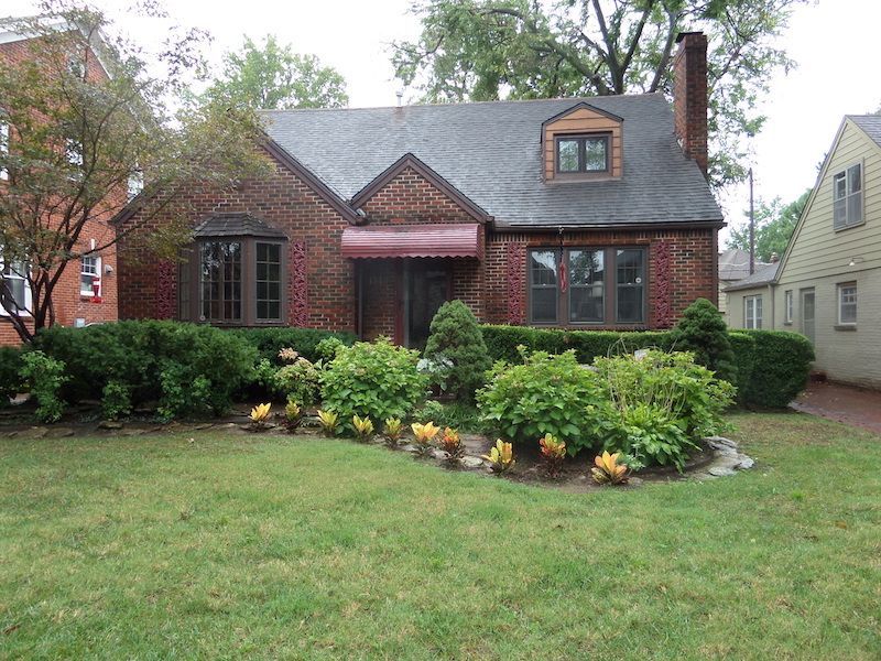 A brick house with a gray roof and a red awning
