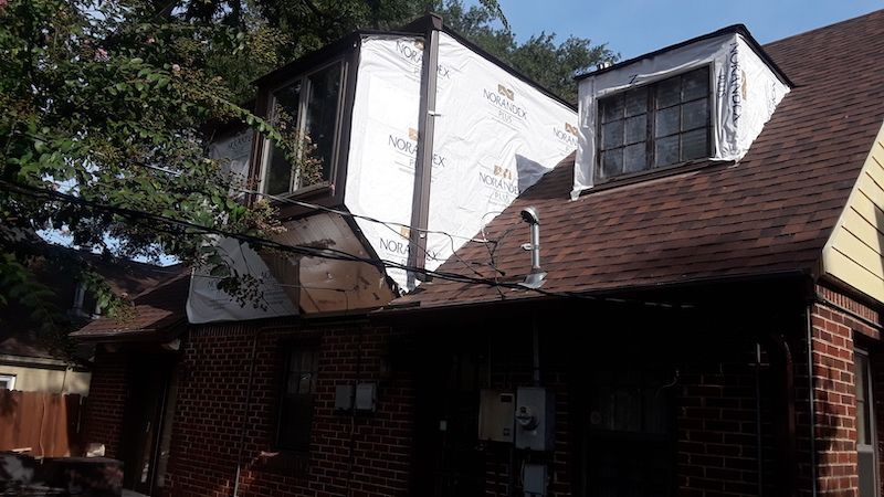 A brick house with a roof that has a window on it.