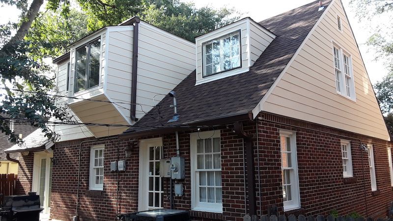 A brick house with a white siding and a brown roof.