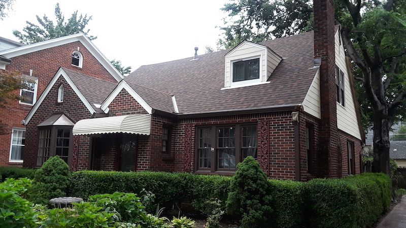 A brick house with a brown roof and a white awning