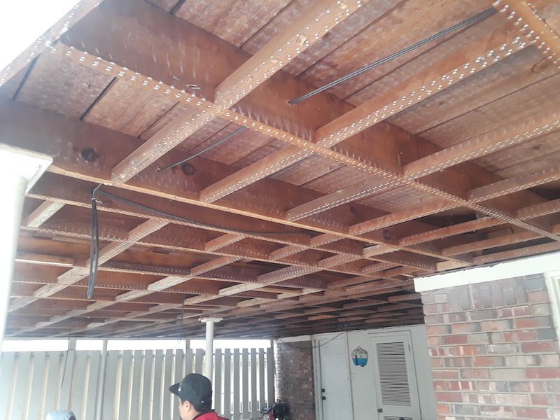 A man in a baseball cap is standing under a wooden ceiling.