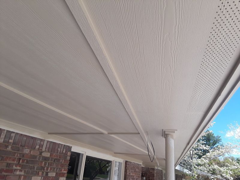 The ceiling of a porch with a white roof and a brick wall.