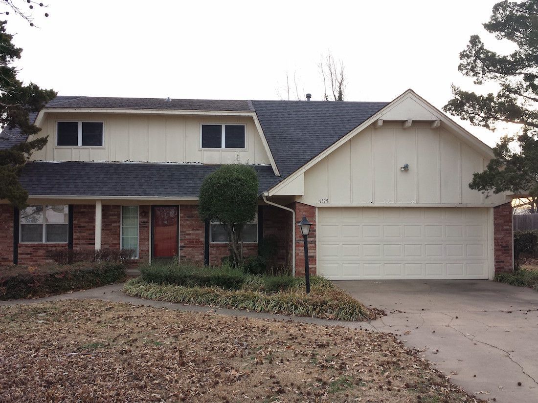 A brick house with a white garage door and a blue roof