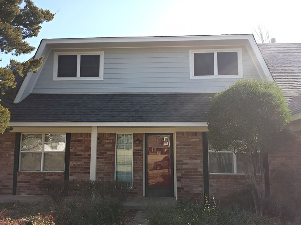 A brick house with a white siding and a black roof