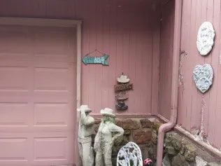 A cute pink house with a matching pink door and two statues standing outside.