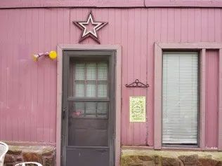 Pink house with a brown door and a start above.