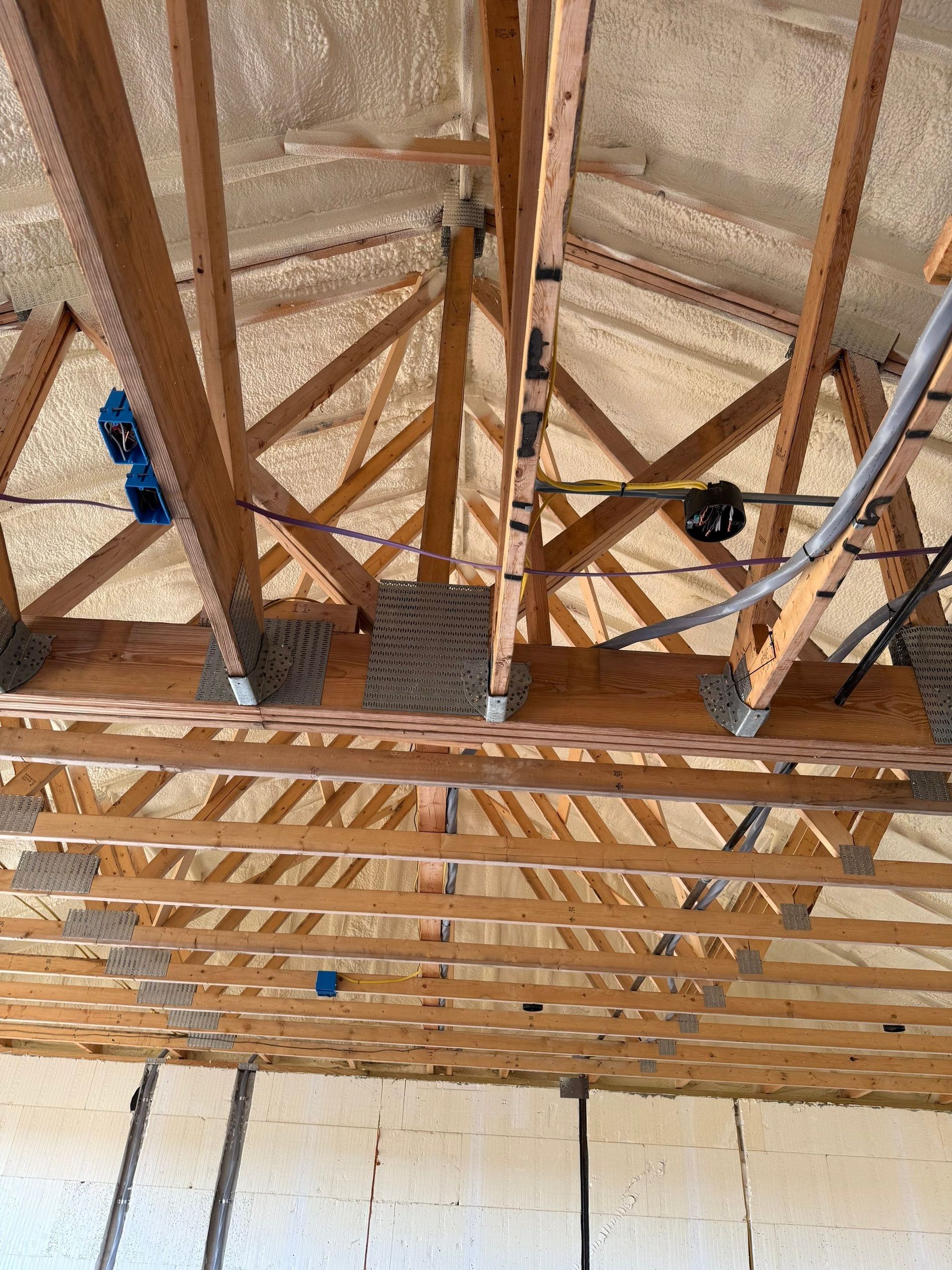 Attic with wooden rafters and spray foam insulation.