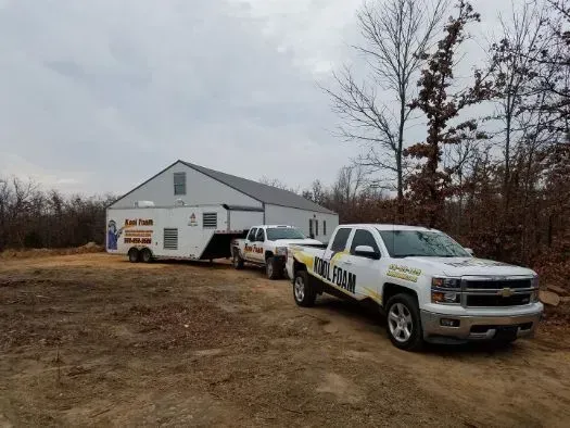 White trucks and a trailer parked near a large building on a cloudy day.