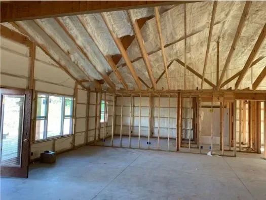 Interior of a building under construction, with exposed wooden beams, insulation, and framing.