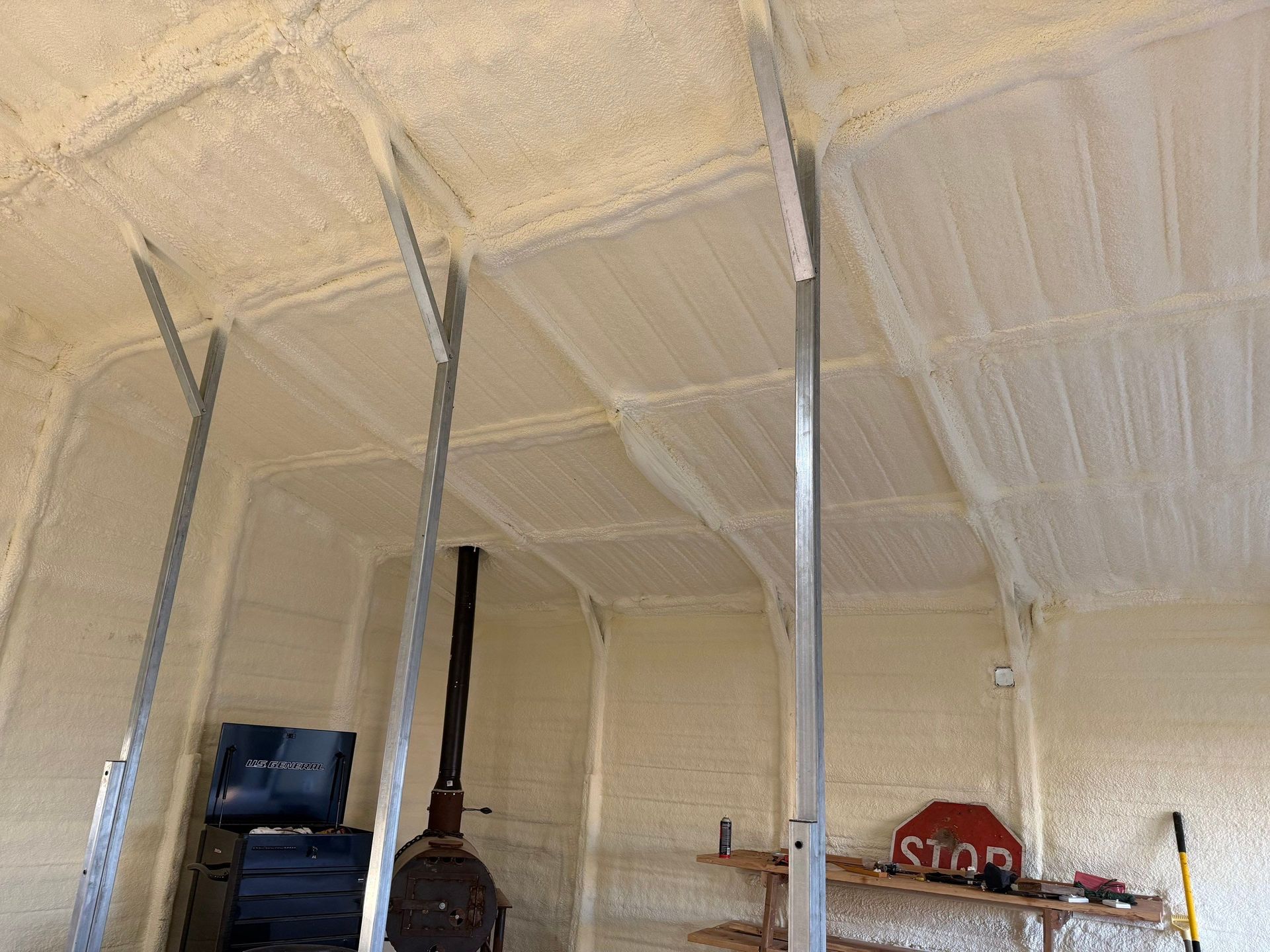 Interior of a building with spray foam insulation on walls and ceiling, metal beams.