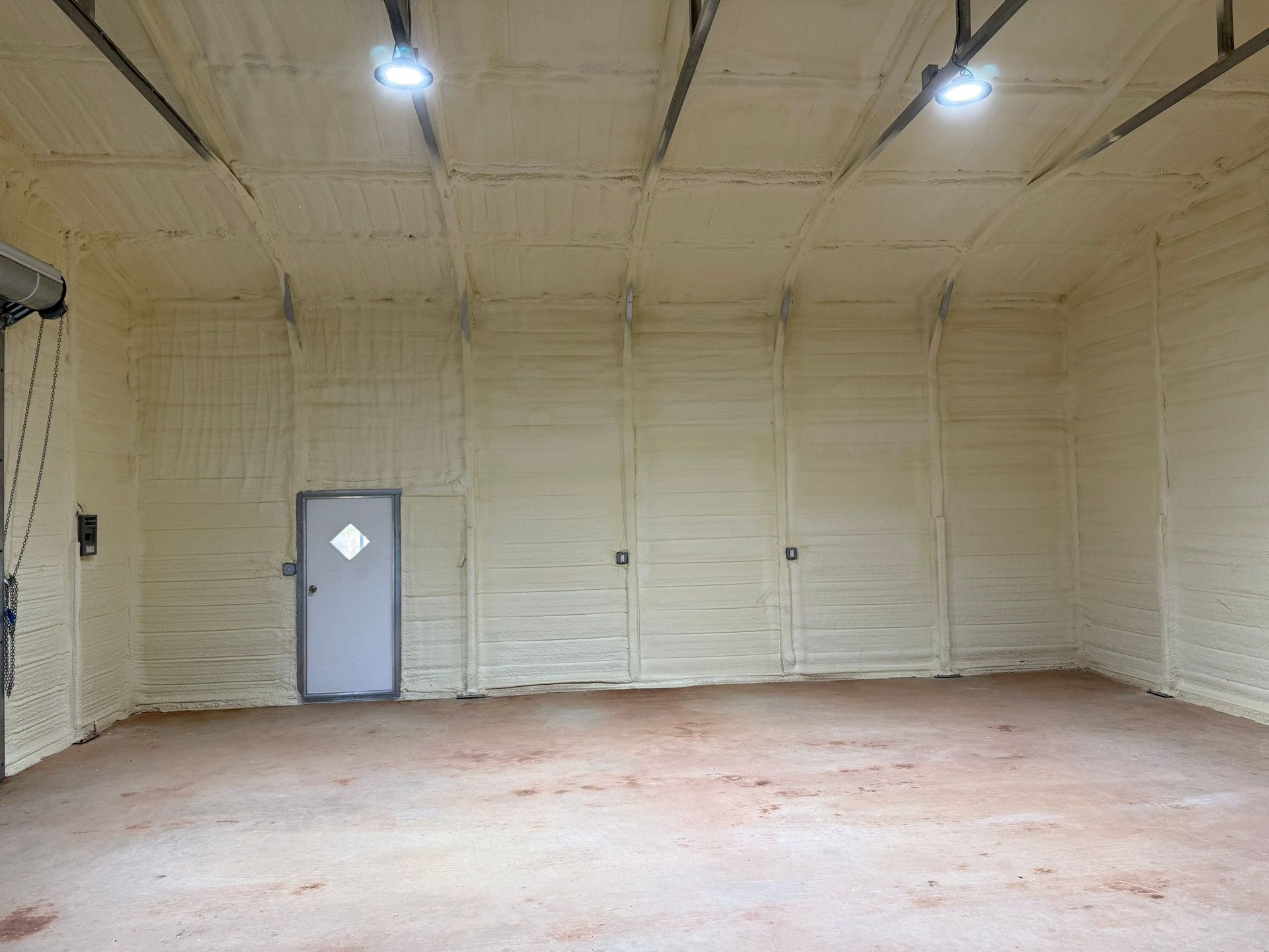 Interior of a building with light brown spray foam insulation on walls and ceiling.