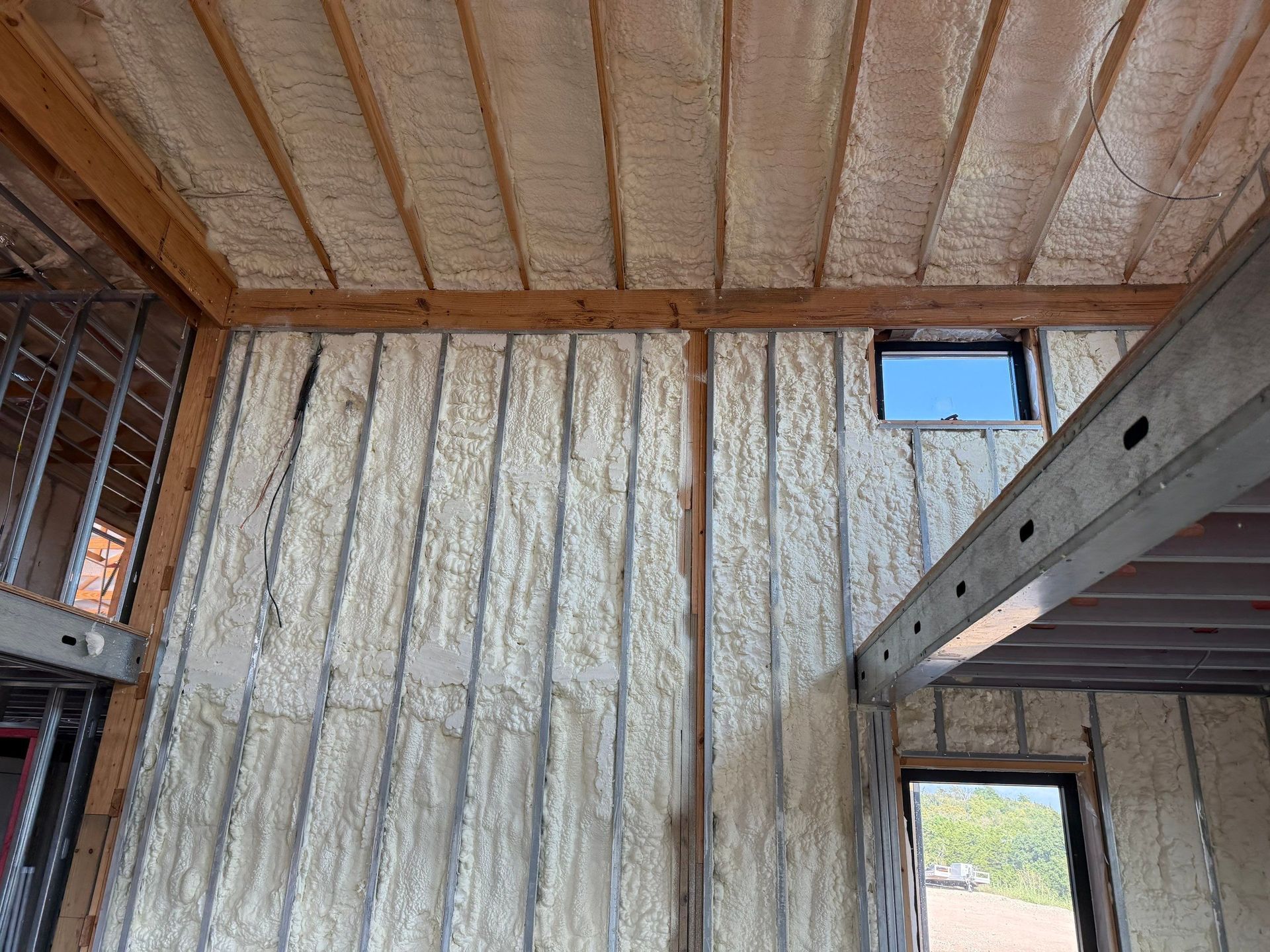 Interior view of a building under construction, spray foam insulation on walls and ceiling.