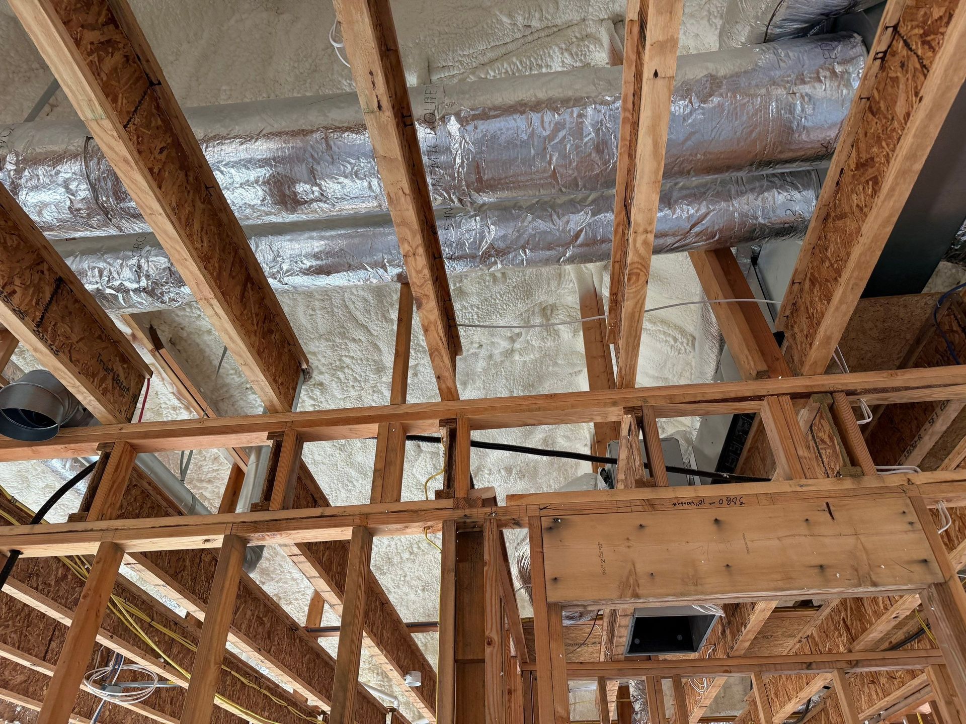 Wooden frame construction, exposed beams, spray foam insulation, ductwork visible, unfinished.