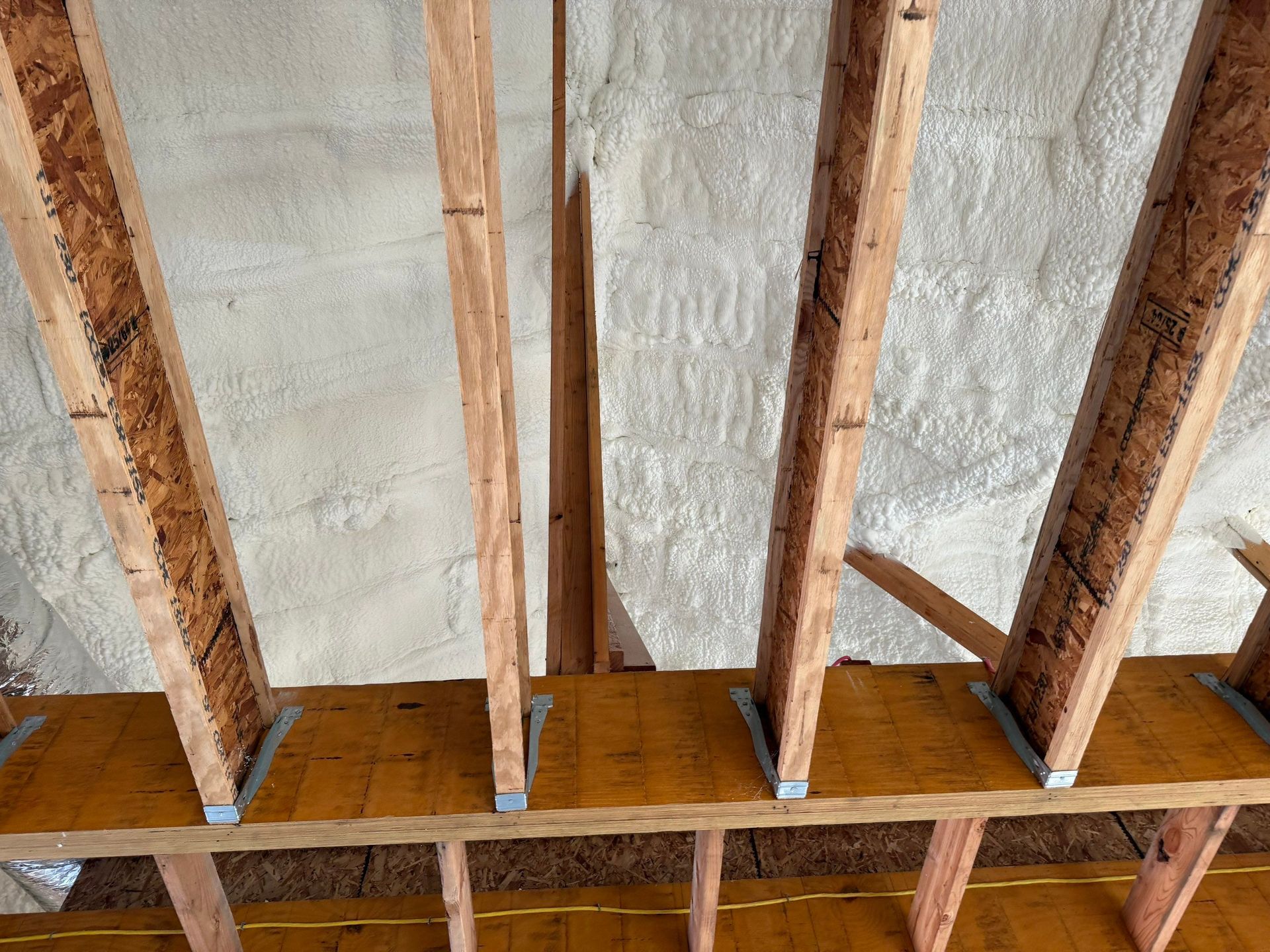 Wooden rafters and beams covered in spray foam insulation.