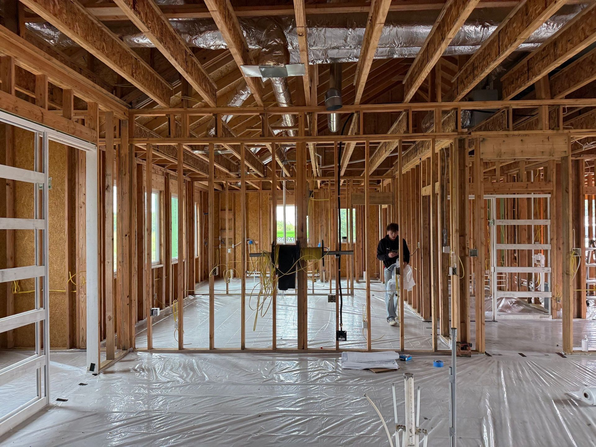 Interior of a building under construction, wooden framework with a worker in the center.