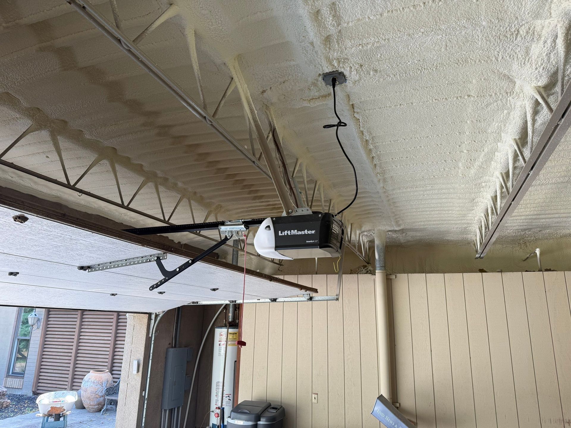 Garage ceiling with garage door opener, insulation, and support beams.