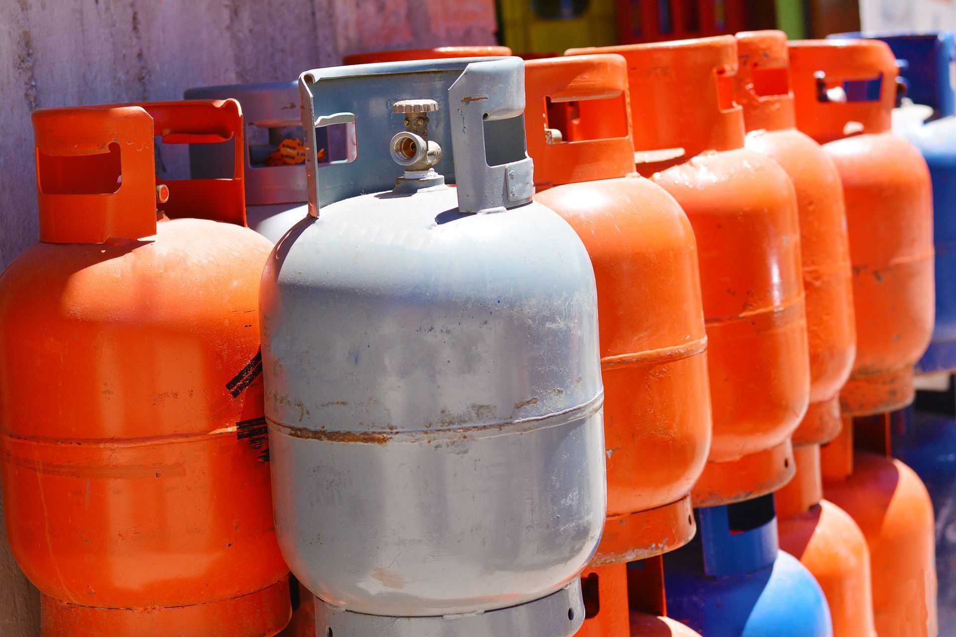 Rows of orange and silver gas cylinders stacked outdoors