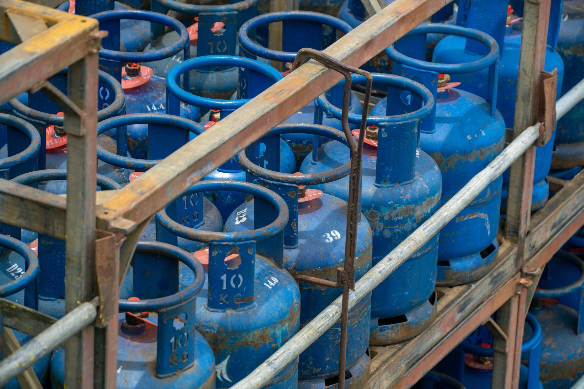 Blue gas cylinders stacked in wooden racks, viewed from above