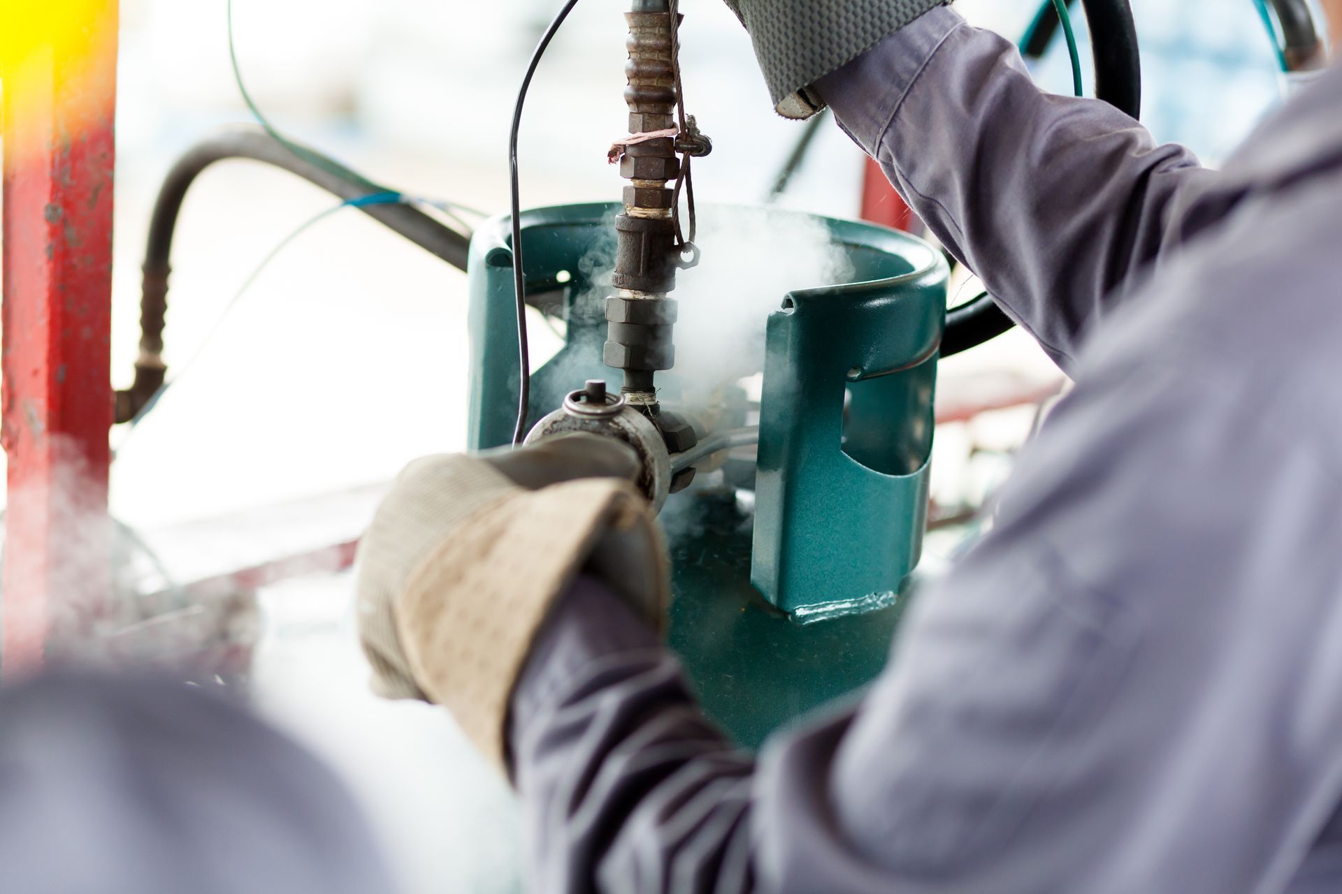 Worker using gloves to repair a green industrial pipe assembly