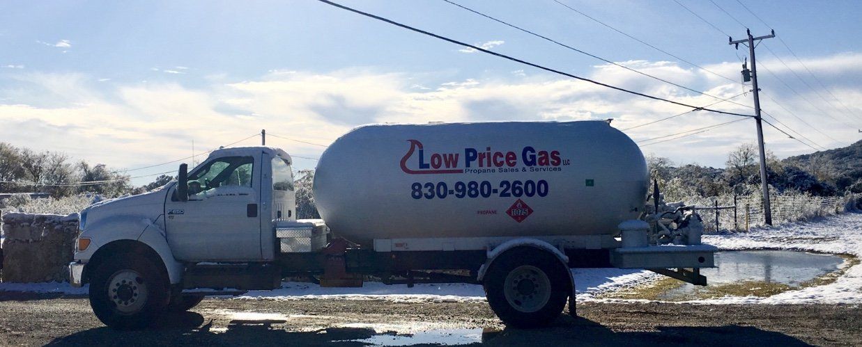 White propane truck with tank logo parked on a snowy roadside under a cloudy sky.