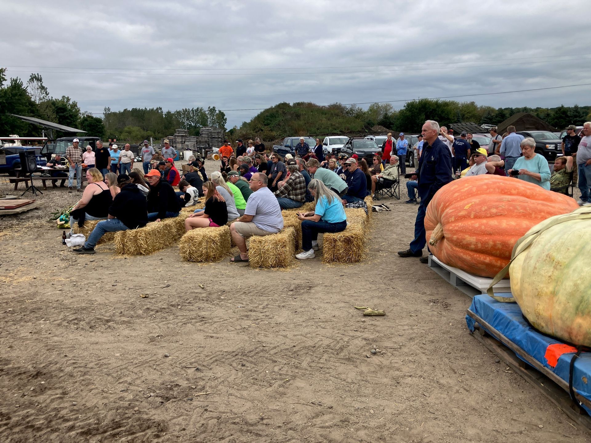 A group of people are sitting on bales of hay in a field.