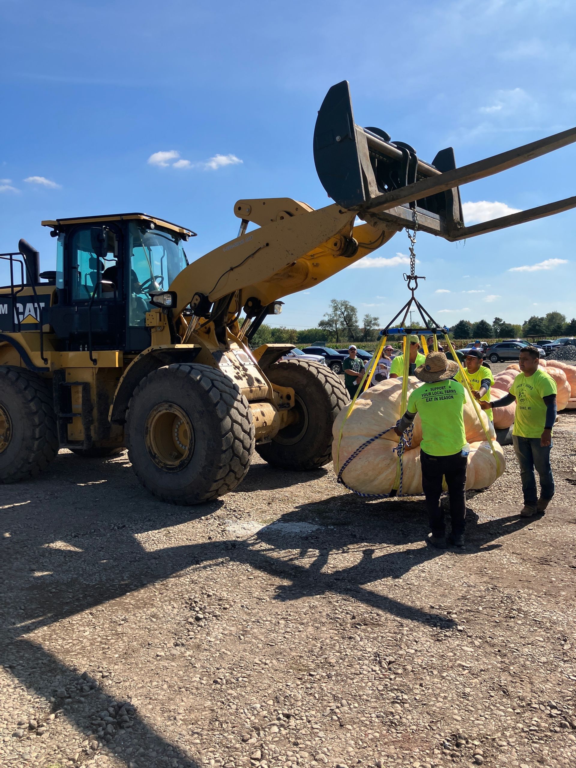 A group of men are standing next to a large yellow tractor.